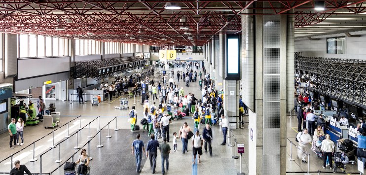 Saguão do aeroporto de Garulhos, em São Paulo, mostrando várias pessoas circulando com bagagens, fazendo check in
