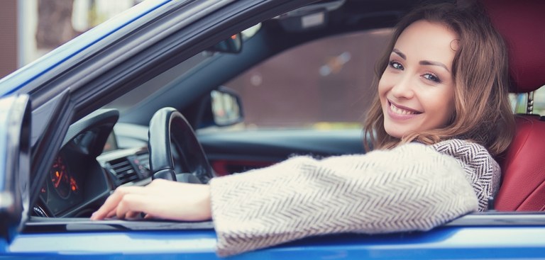 Fotografia de uma motorista parada no trânsito e olhando pela janela do carro