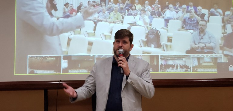 Superintendente de Operações do Serpro - Heitor Rapcinski - fala ao público no auditório - exibido na tela atrás dele