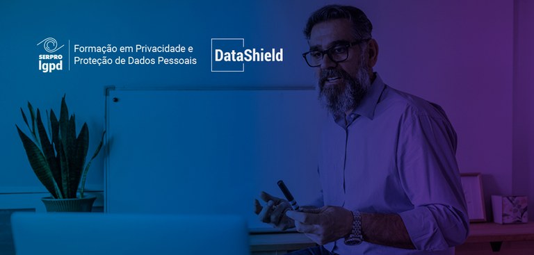 Fotografia de um professor interagindo com alunos por meio de um computador. Acima e à esquerda, marcas do Serpro LGPD e Datashield Fotografia de um professor interagindo com alunos por meio de um computador. Acima e à esquerda, marcas do Serpro LGPD e Datashield