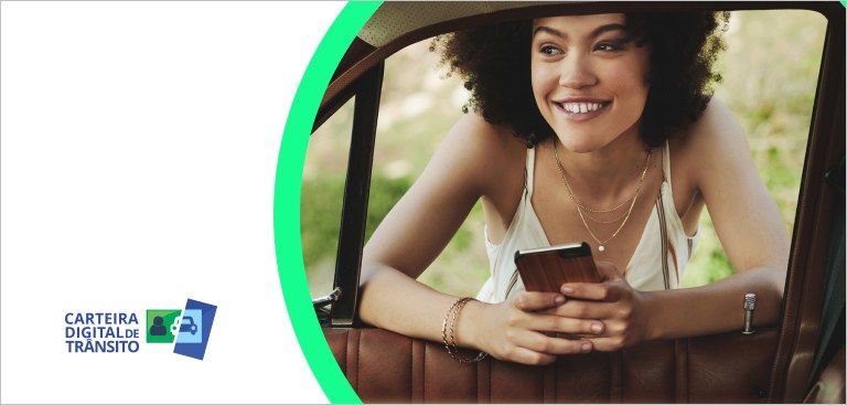 Apoiada na janela de um carro, mulher sorri com um celular nas mãos. À esquerda, aplicação da marca do app Carteira Nacional de Trânsito (CDT) Apoiada na janela de um carro, mulher sorri com um celular nas mãos. À esquerda, aplicação da marca do app Carteira Nacional de Trânsito (CDT)