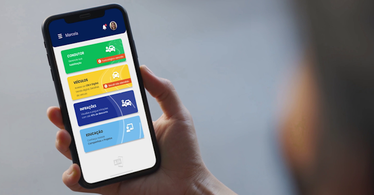 Detalhe de uma mão segurando um celular cuja tela exibe o aplicativo da Carteira Digital de Trânsito (CDT) Detalhe de uma mão segurando um celular cuja tela exibe o aplicativo da Carteira Digital de Trânsito (CDT)