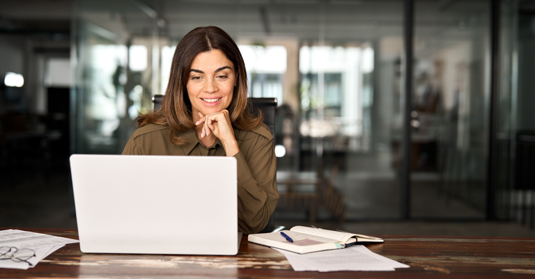 Fotografia de uma mulher trabalhando em um computador e sorrindo Fotografia de uma mulher trabalhando em um computador e sorrindo