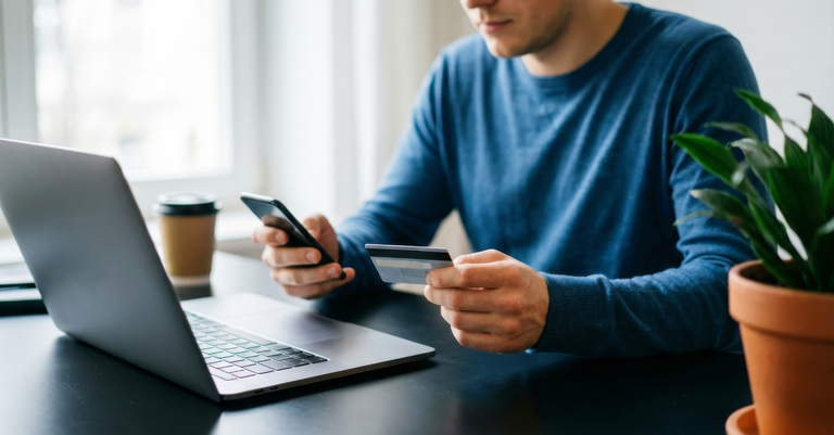 Fotografia de uma pessoa usando um cartão de crédito para fazer um pagamento pela internet em seu laptop Fotografia de uma pessoa usando um cartão de crédito para fazer um pagamento pela internet em seu laptop