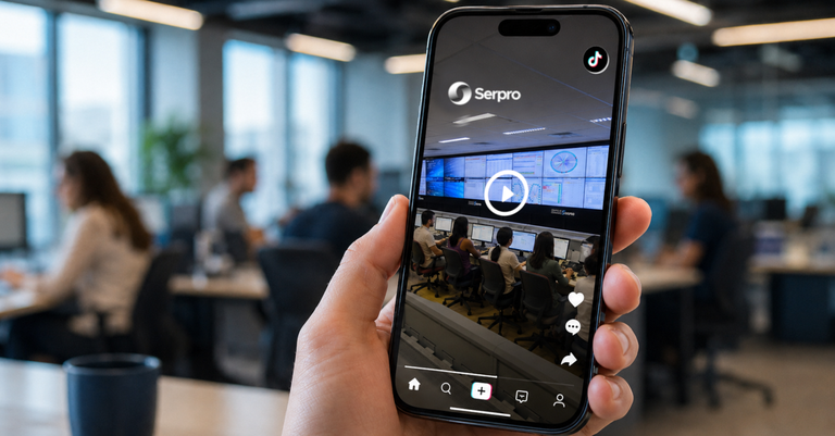 Pessoa segura um celular exibindo vídeo do Serpro no TikTok, com ambiente de trabalho desfocado ao fundo. Pessoa segura um celular exibindo vídeo do Serpro no TikTok, com ambiente de trabalho desfocado ao fundo.